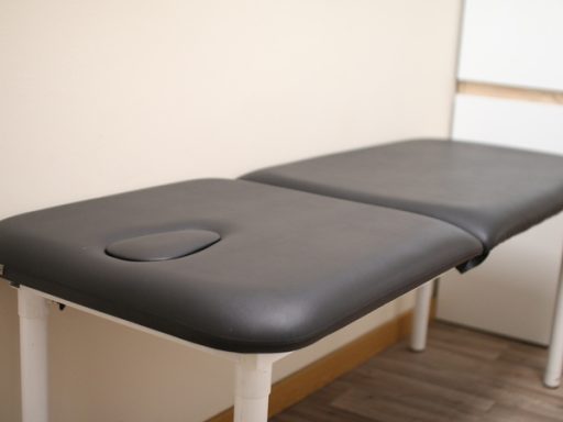 Mesa de tratamiento médico con tapizado oscuro y abertura para la cara.