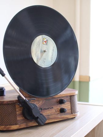 Disco de vinilo sobre un tocadiscos vintage, con un estilo clásico en una mesa.